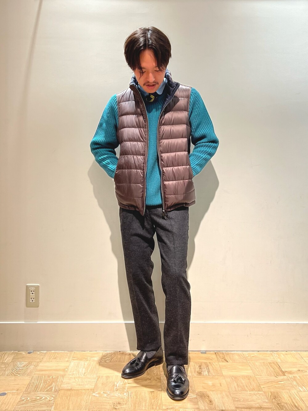 ブラウン系のダウンベスト、ブラック系のハンドバッグを着用したメンズの春コーディネートの5枚目の写真