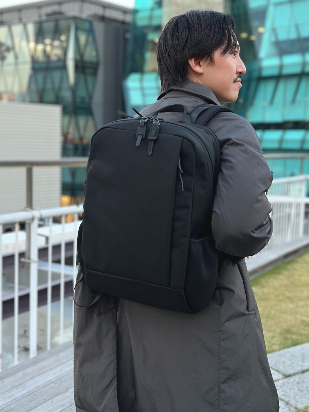 グレー系のダウンジャケット/コート、ブルー系のニット/セーター、ブラック系のバックパック/リュックを着用したメンズの冬コーディネートの8枚目の写真