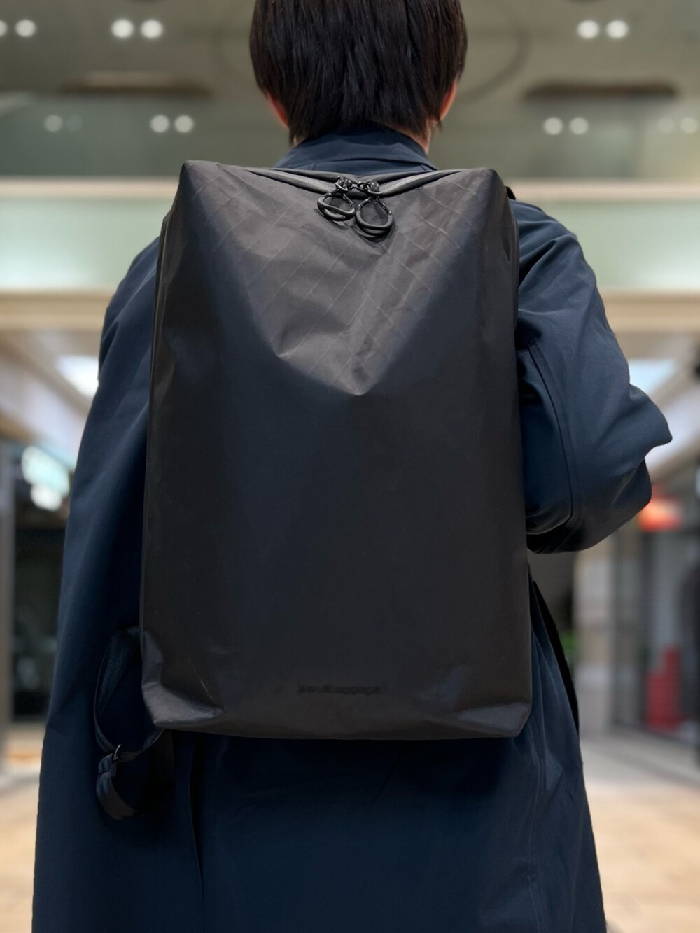 ブラック系のバックパック/リュック、ブルー系のステンカラーコート、ブラック系のシューズを着用したメンズの秋コーディネートの7枚目の写真