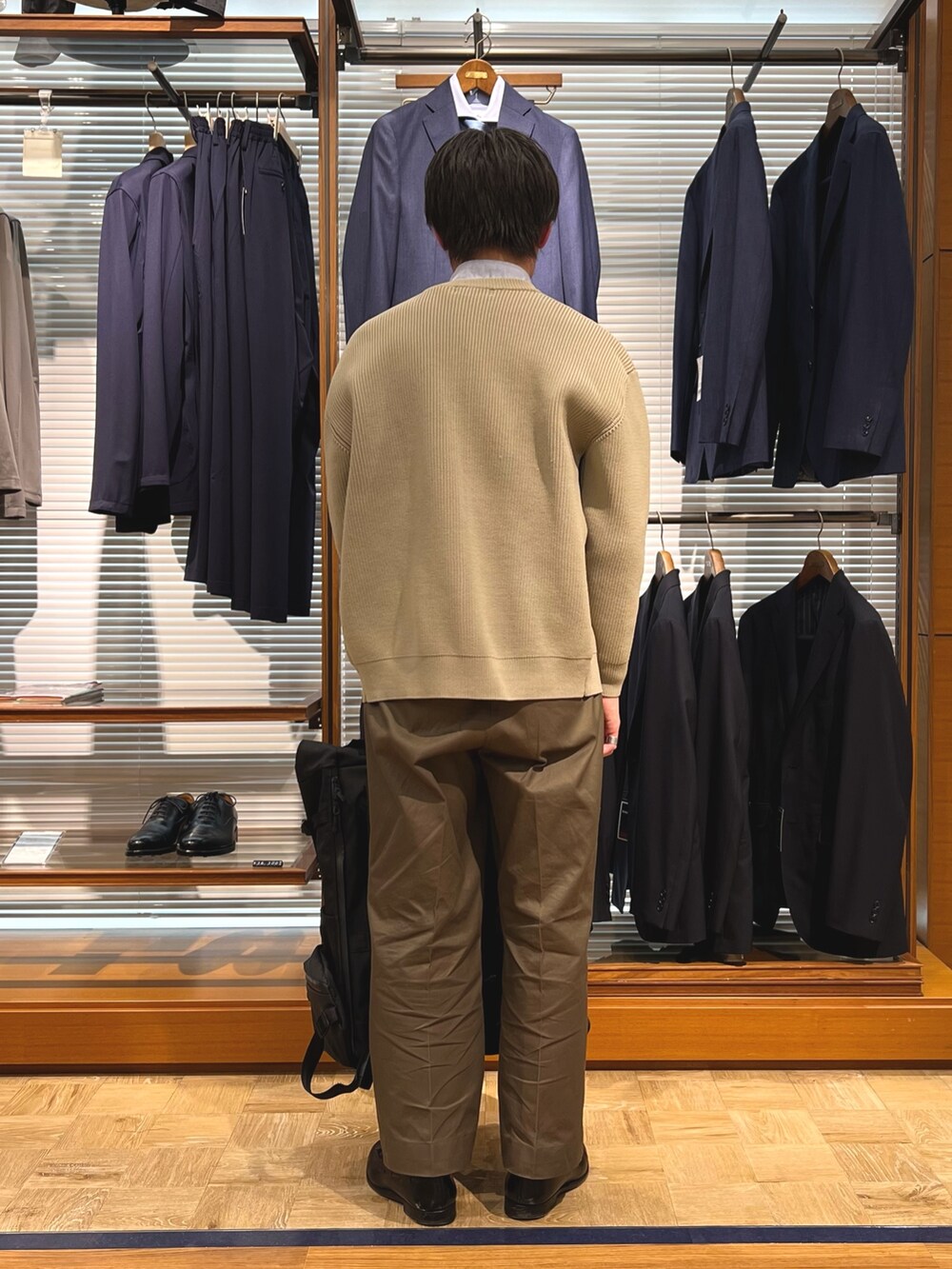 ベージュ系のカーディガン/ボレロ、ブラック系のバックパック/リュック、ブラック系のローファーを着用したメンズの春コーディネートの5枚目の写真