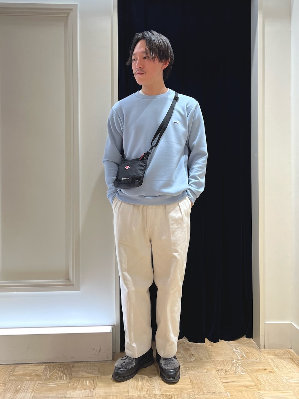 ブルー系のスウェット、ブラック系のショルダーバッグ、ブラック系のシューズを着用したメンズの春コーディネートの2枚目の写真