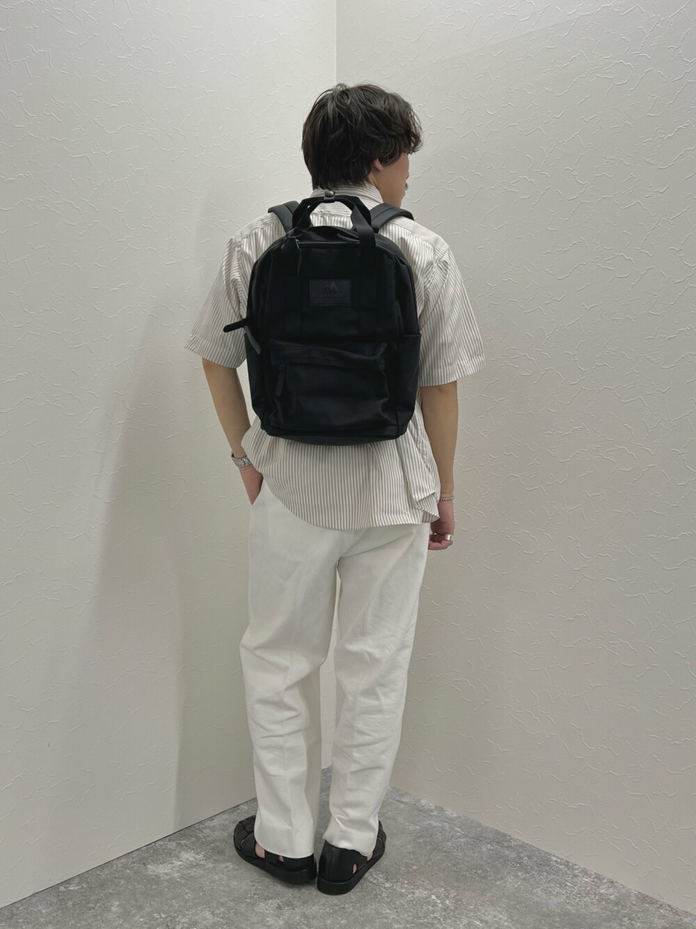 ホワイト系のTシャツ/カットソー、ブラック系のバックパック/リュック、ホワイト系のデニムパンツを着用したメンズの春コーディネートの4枚目の写真