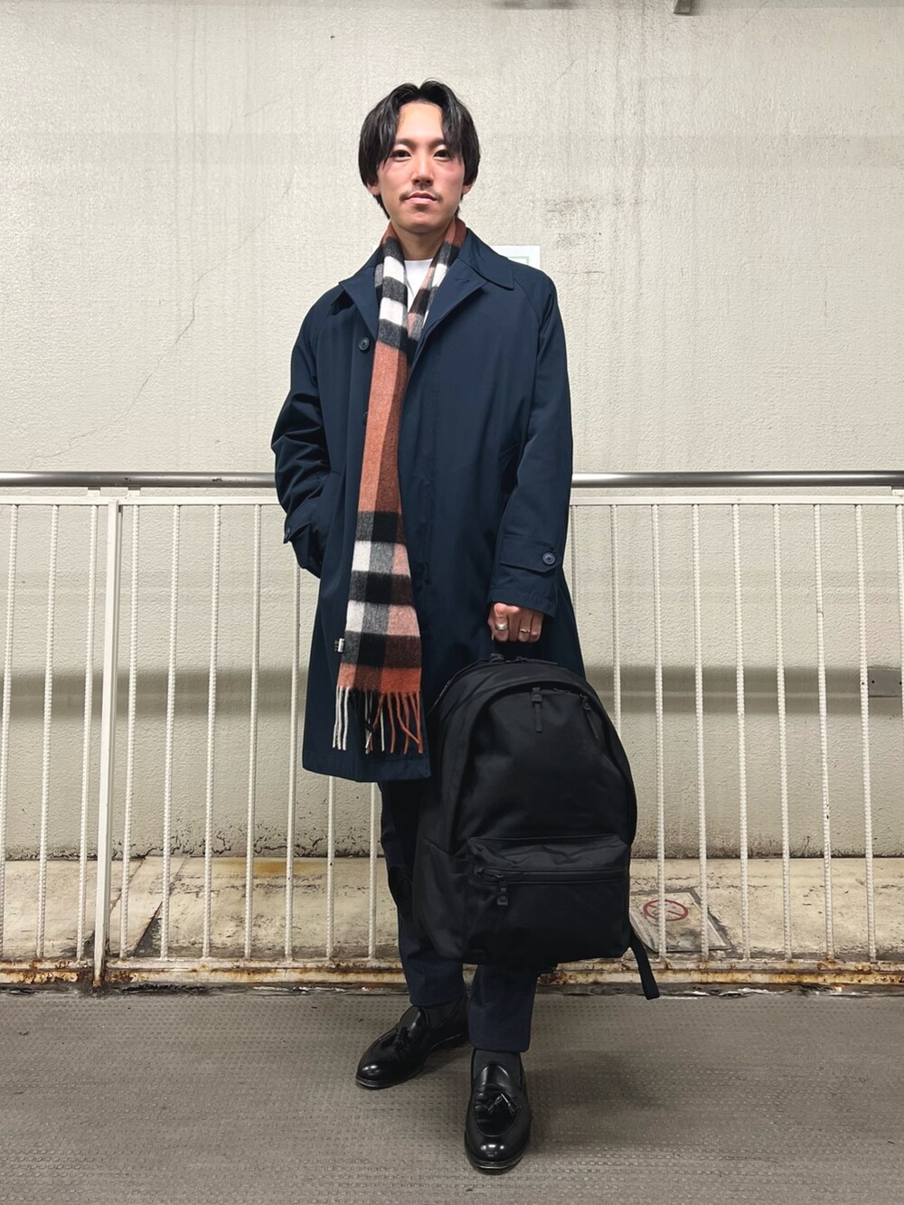 ブラック系のバックパック/リュック、ホワイト系のTシャツ/カットソー、ブルー系のステンカラーコートを着用したメンズの秋コーディネートの2枚目の写真