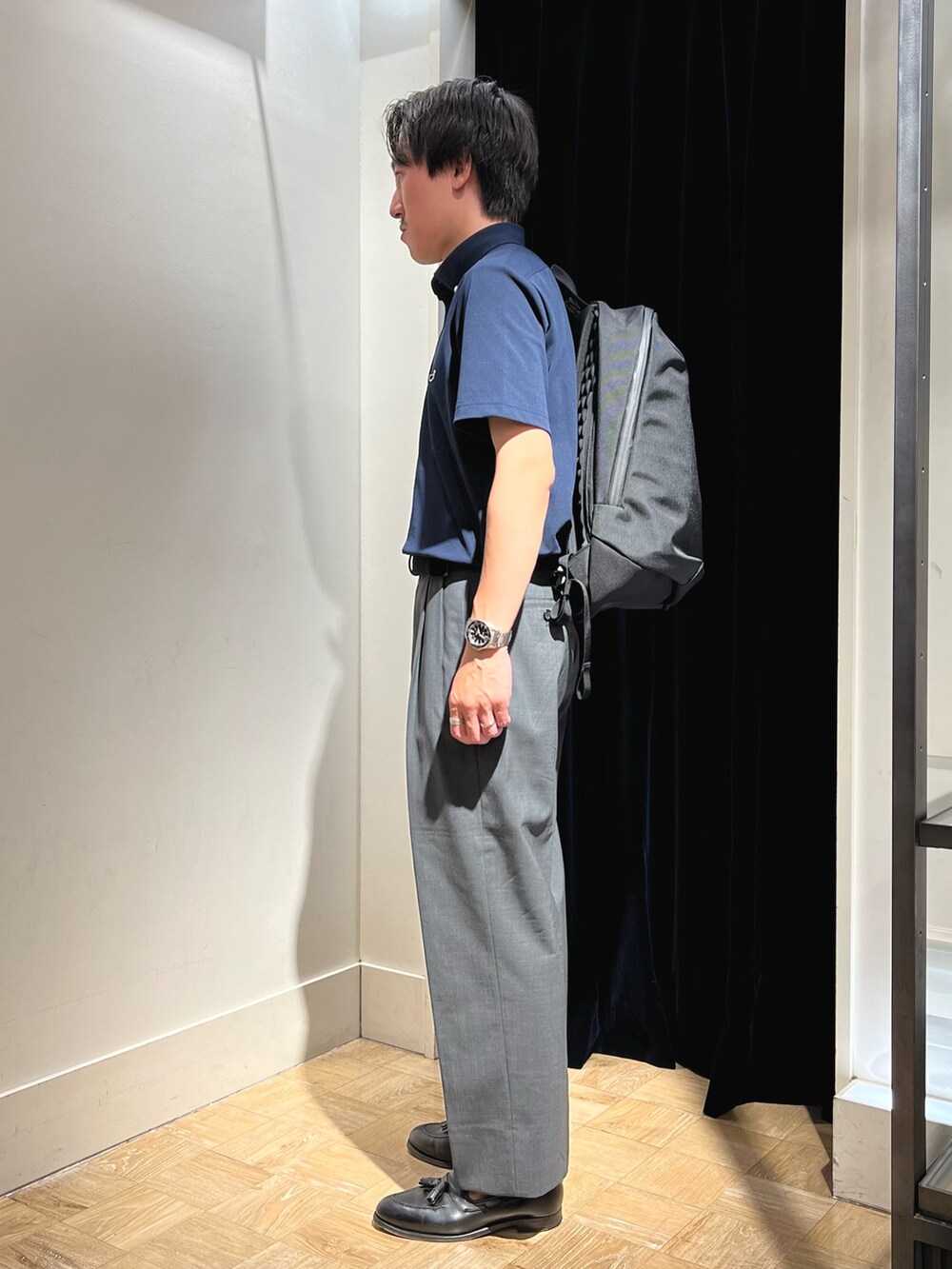 ブルー系のポロシャツ、ブラック系のバックパック/リュック、ブラック系のベルトを着用したメンズの夏コーディネートの4枚目の写真