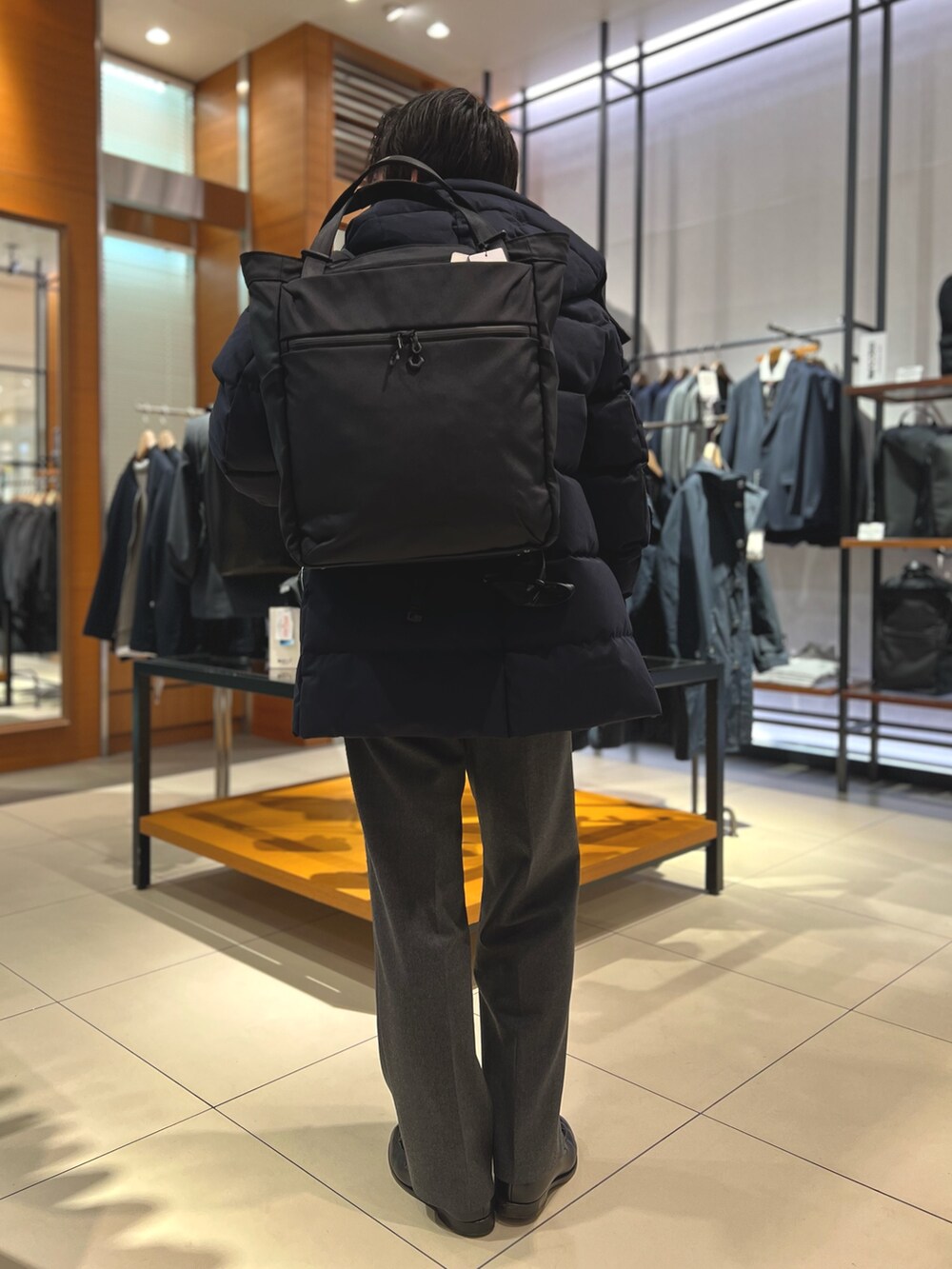 ブルー系のダウンジャケット/コート、ブラック系のトートバッグ、ブラック系のローファーを着用したメンズの冬コーディネートの8枚目の写真