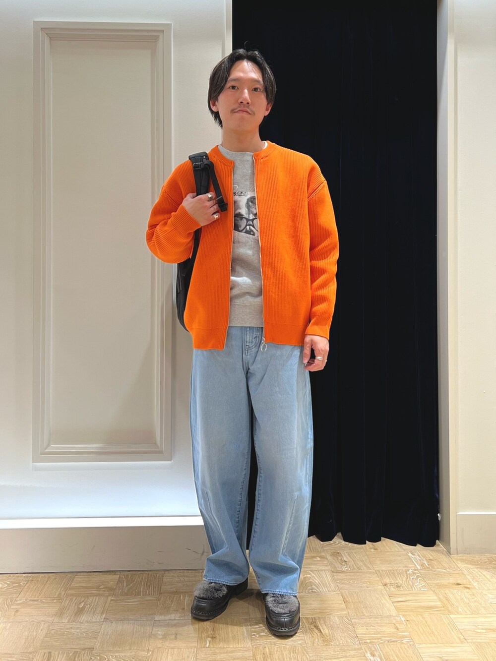 グレー系のスウェット、オレンジ系のカーディガン/ボレロ、ブラック系のシューズを着用したメンズの冬コーディネートの2枚目の写真