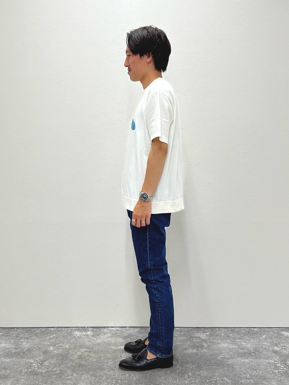 ホワイト系のTシャツ/カットソー、ブルー系のデニムパンツ、ブラック系のローファーを着用したメンズの夏コーディネートの4枚目の写真