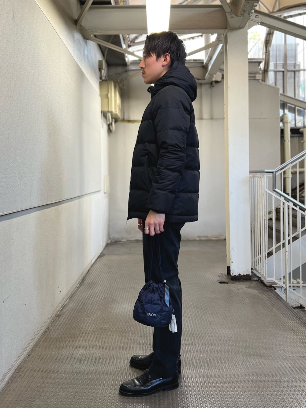 ブラック系のダウンジャケット/コート、ブルー系のショルダーバッグ、ブルー系のその他パンツを着用したメンズの冬コーディネートの3枚目の写真