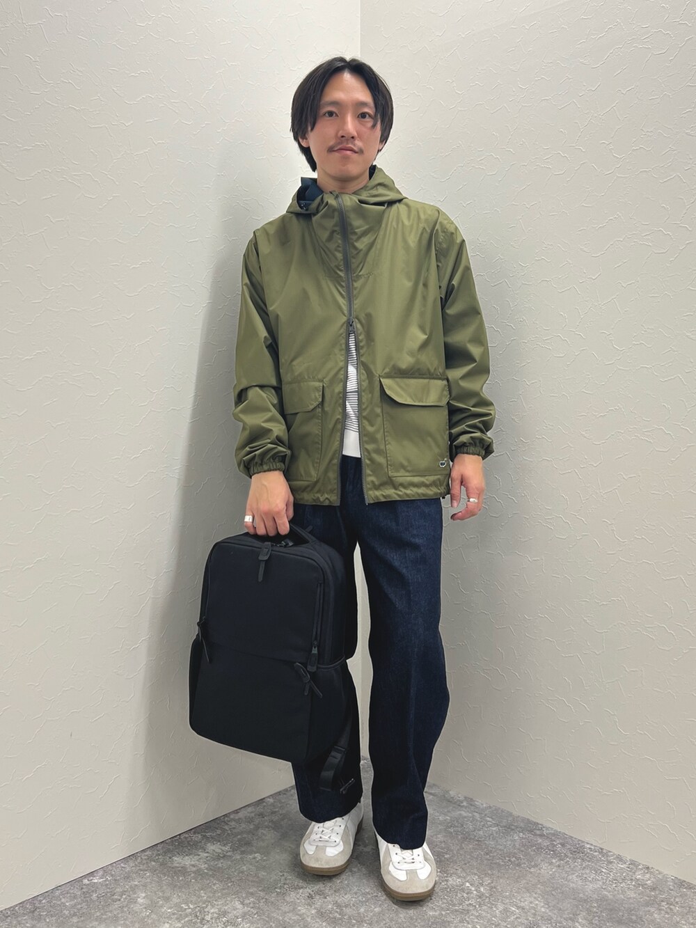 グリーン系のブルゾン、ホワイト系のTシャツ/カットソー、ブルー系のデニムパンツを着用したメンズの冬コーディネートの5枚目の写真