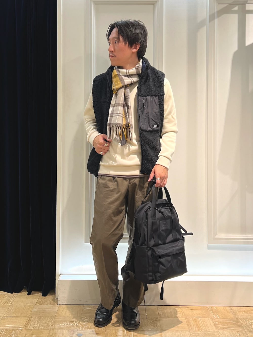 ブラック系のダウンベスト、ホワイト系のTシャツ/カットソー、ブラック系のバックパック/リュックを着用したメンズの秋コーディネートの2枚目の写真