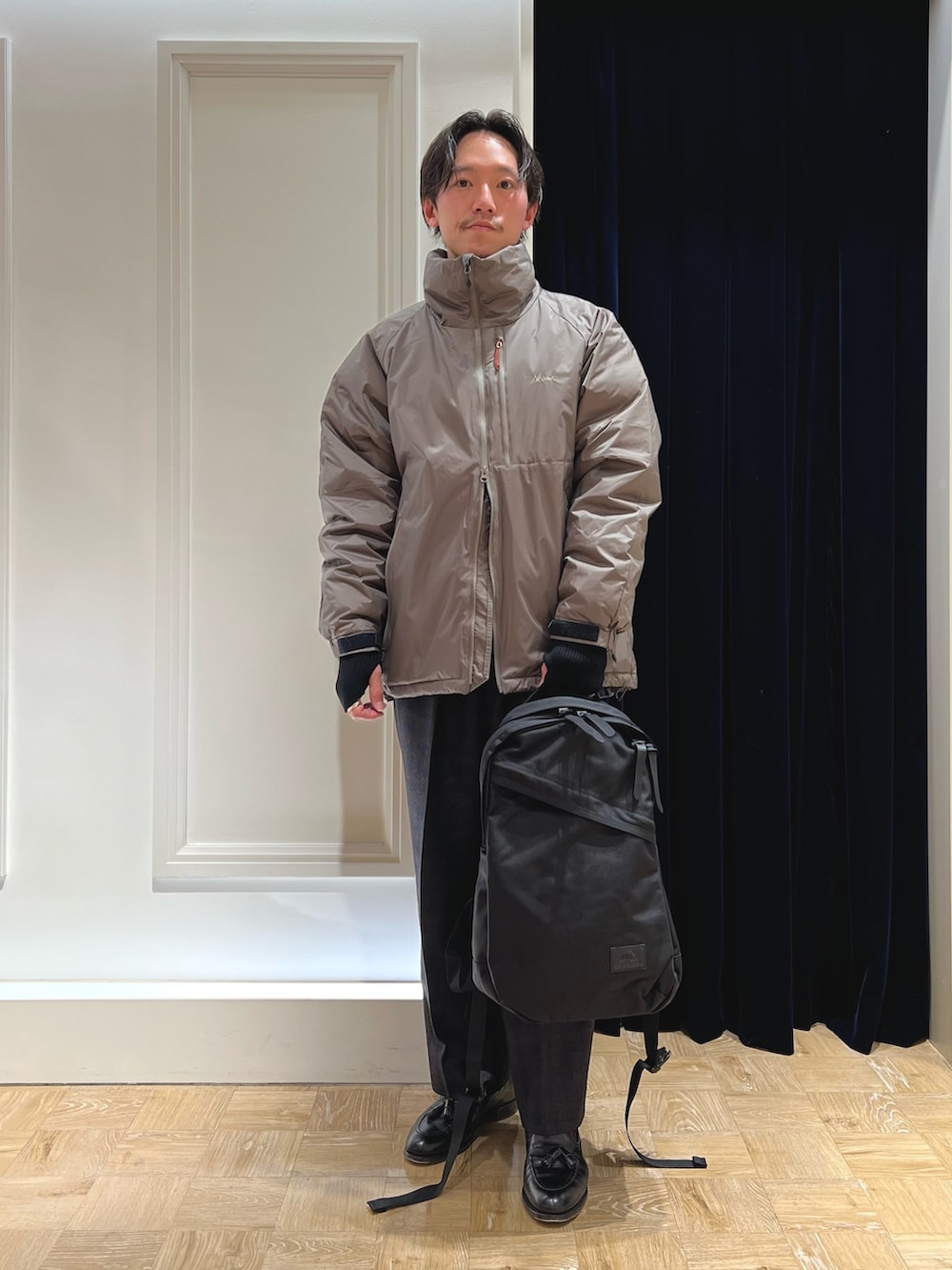 グレー系のダウンジャケット/コート、ブラック系のバックパック/リュックを着用したメンズの冬コーディネートの2枚目の写真