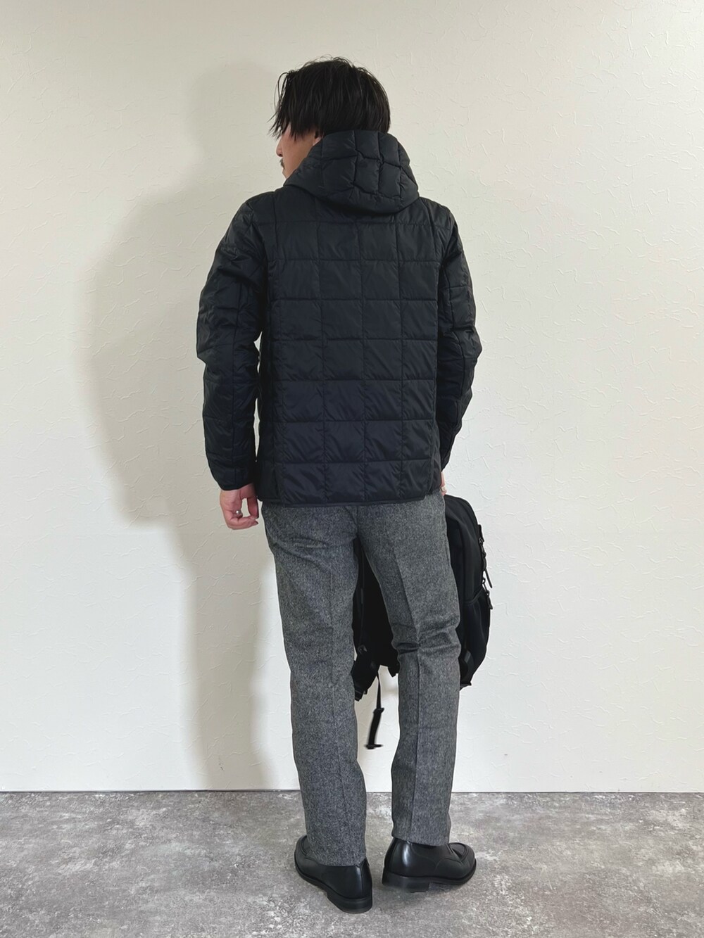 ブラック系のダウンジャケット/コート、レッド系のニット/セーター、グレー系のスラックスを着用したメンズの秋コーディネートの6枚目の写真