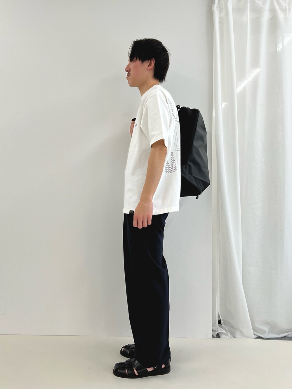 ホワイト系のTシャツ/カットソー、グレー系のバックパック/リュック、ブラック系のその他パンツを着用したメンズの春コーディネートの3枚目の写真