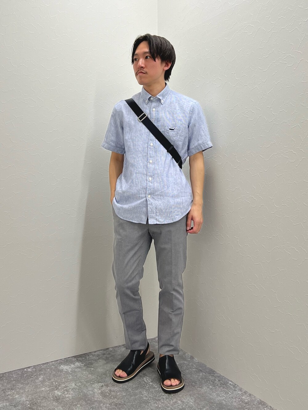 ブルー系のシャツ/ブラウス、ブラック系のボディバッグ/ウエストポーチ、グレー系のチノパンツを着用したメンズの春コーディネートの3枚目の写真