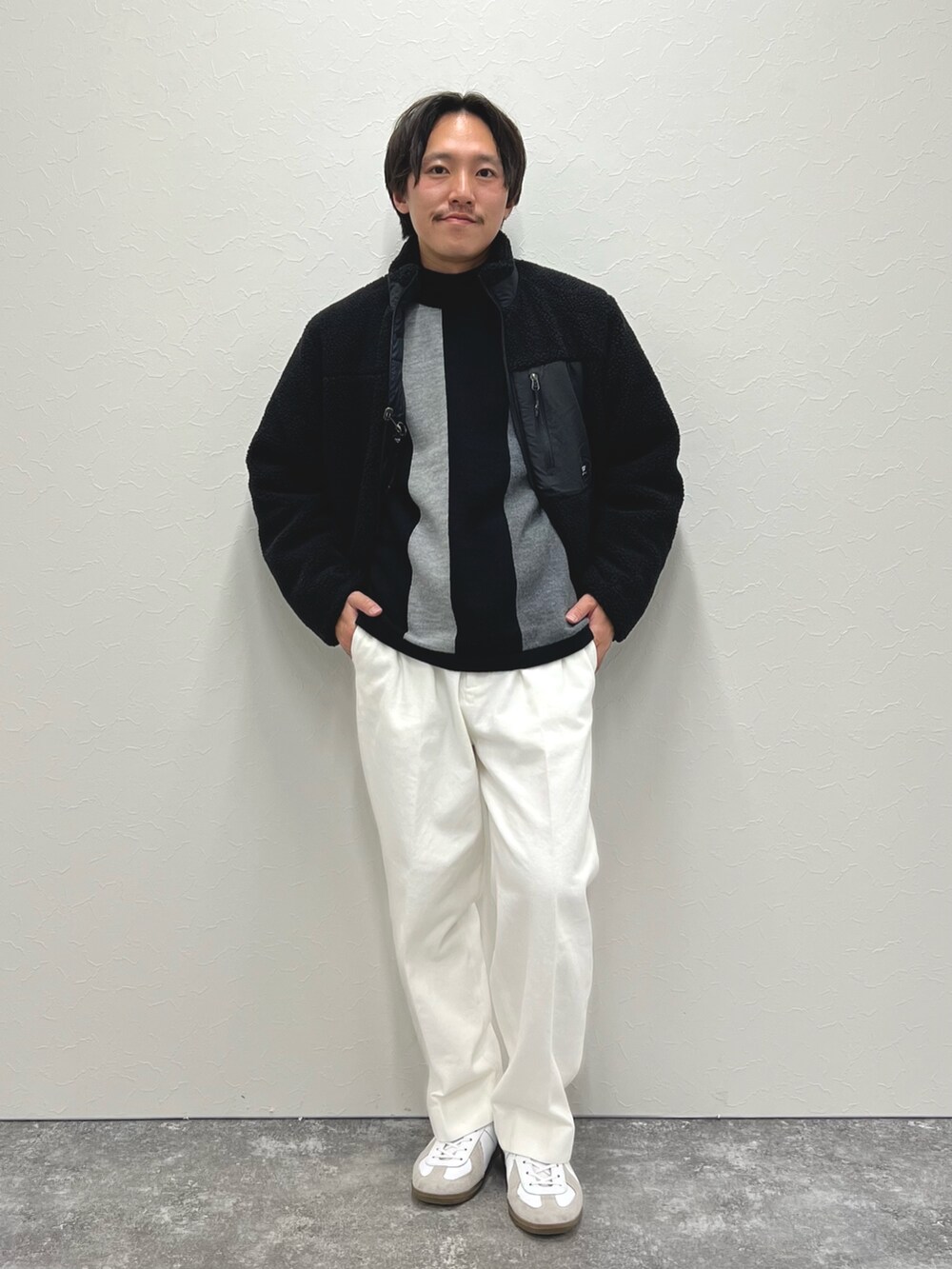 ブラック系のニット/セーター、ホワイト系のデニムパンツ、ブラック系のブルゾンを着用したメンズの冬コーディネートの3枚目の写真