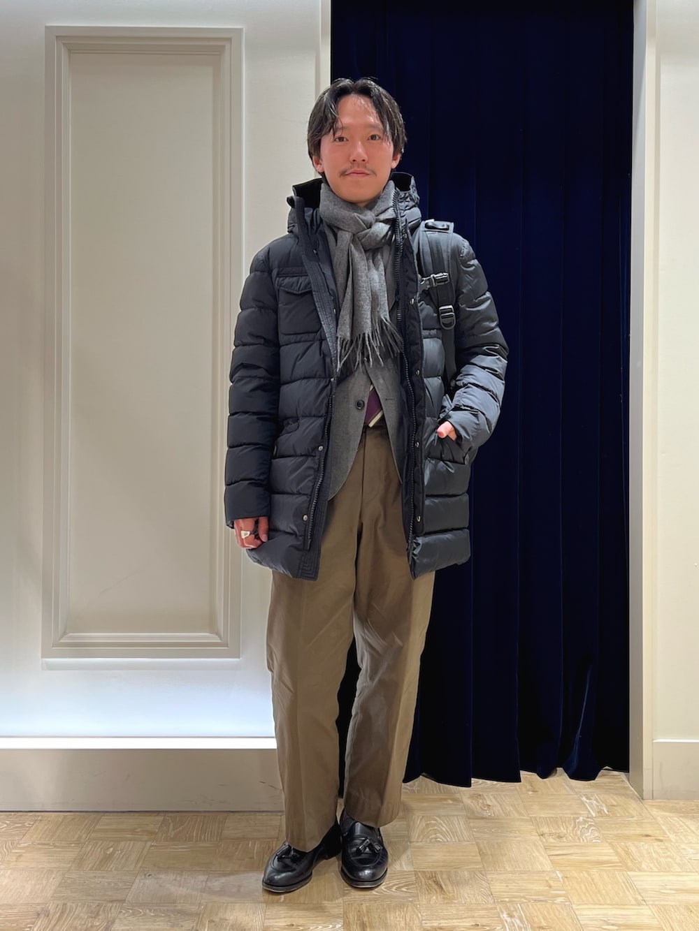 グレー系のテーラードジャケット、ブラック系のバックパック/リュック、ブラック系のダウンジャケット/コートを着用したメンズの冬コーディネートの2枚目の写真