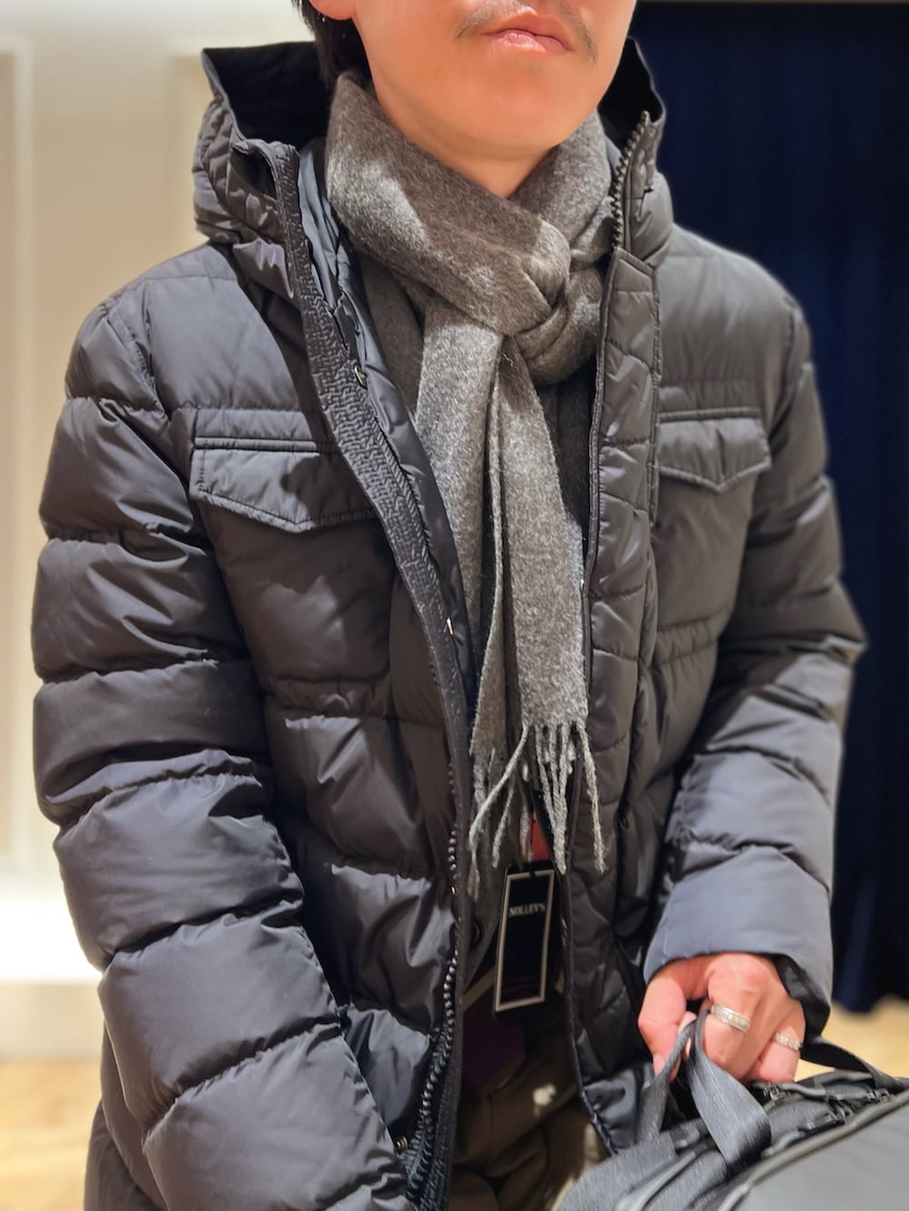 グレー系のテーラードジャケット、ブラック系のバックパック/リュック、ブラック系のダウンジャケット/コートを着用したメンズの冬コーディネートの6枚目の写真