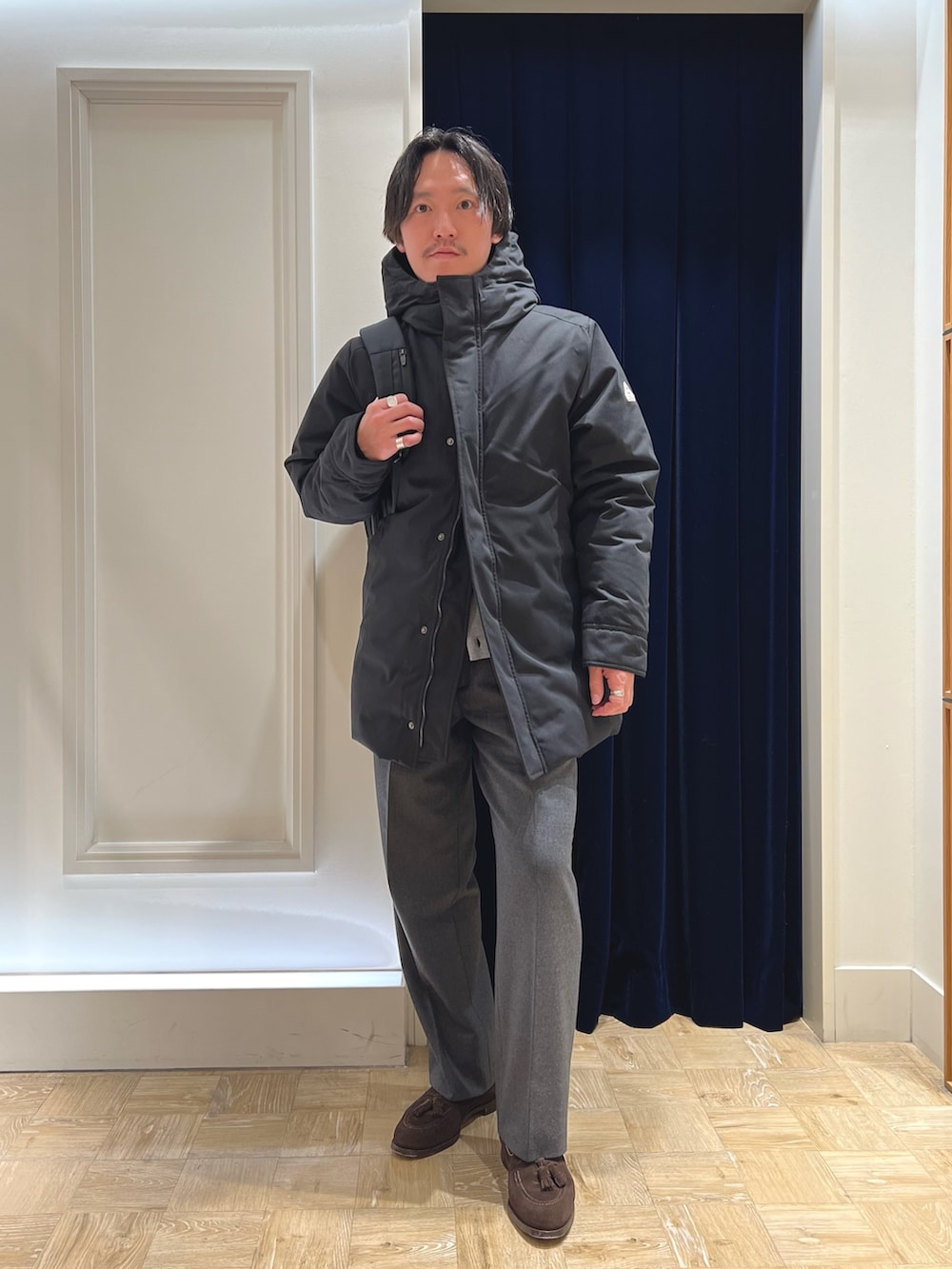 ブラック系のダウンジャケット/コート、グレー系のカーディガン/ボレロ、ブラック系のバックパック/リュックを着用したメンズの冬コーディネートの4枚目の写真