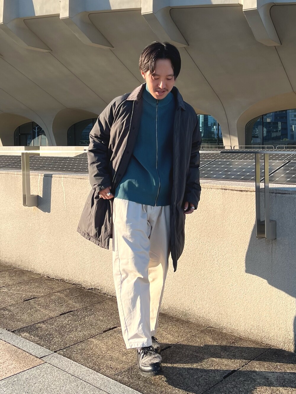 グレー系のダウンジャケット/コート、ブルー系のニット/セーター、ブラック系のその他シューズを着用したメンズの秋コーディネートの4枚目の写真