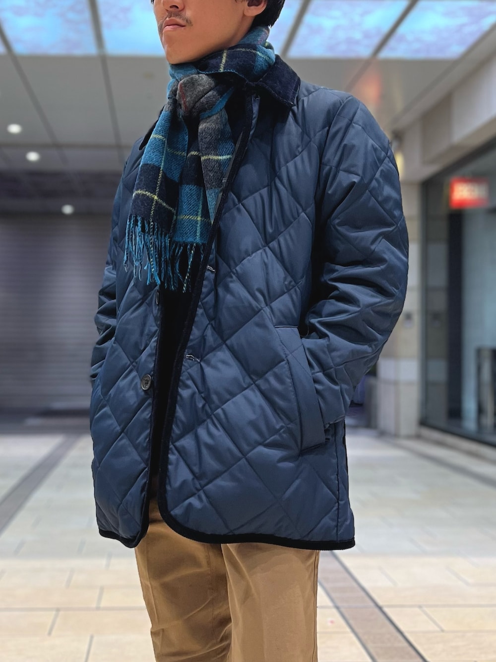 ブルー系のダウンジャケット/コート、ベージュ系のチノパンツ、ブルー系のニット/セーターを着用したメンズの冬コーディネートの2枚目の写真