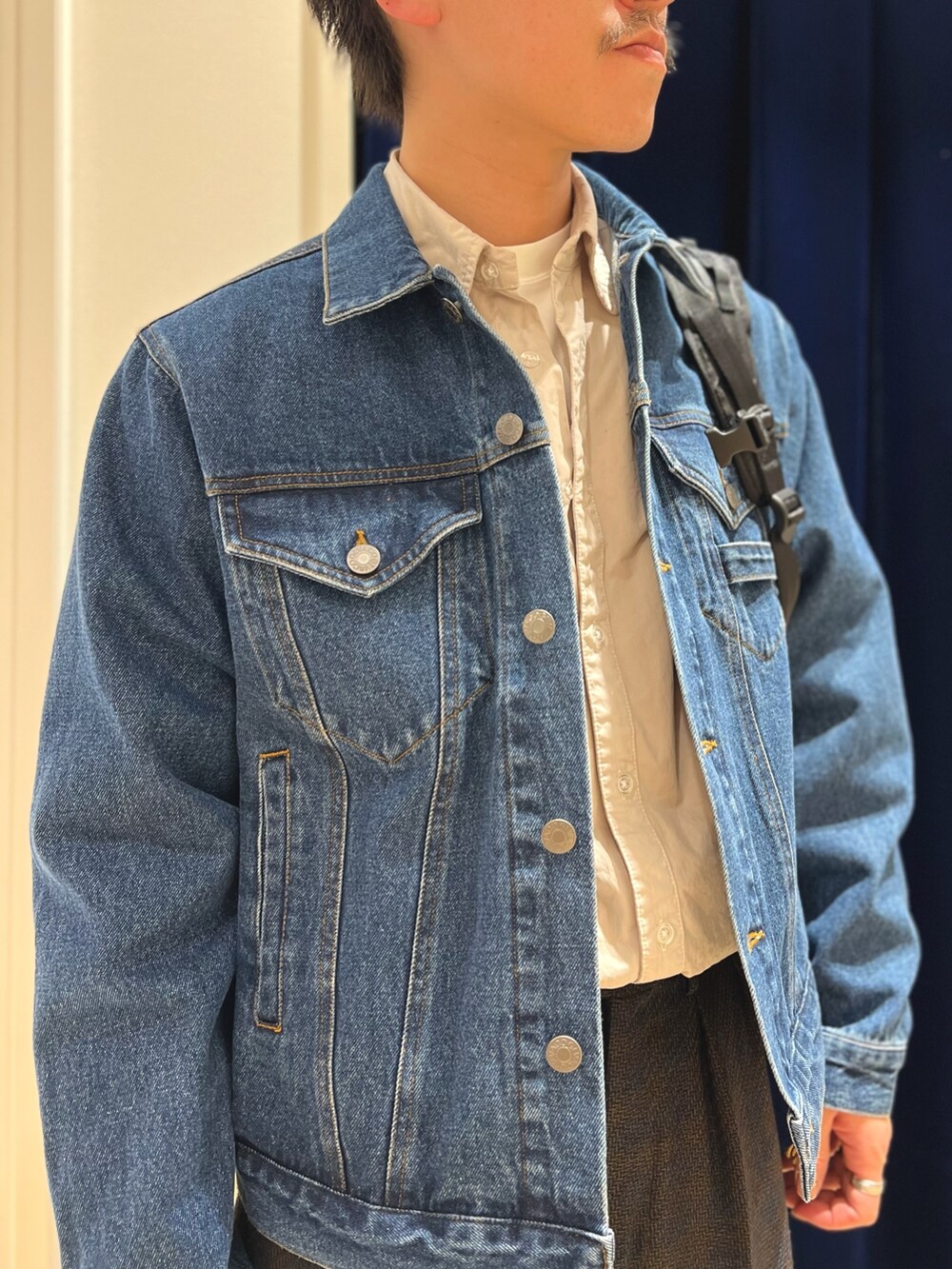 ブルー系のデニムジャケット、ベージュ系のシャツ/ブラウス、ブラック系のバックパック/リュックを着用したメンズの冬コーディネートの6枚目の写真