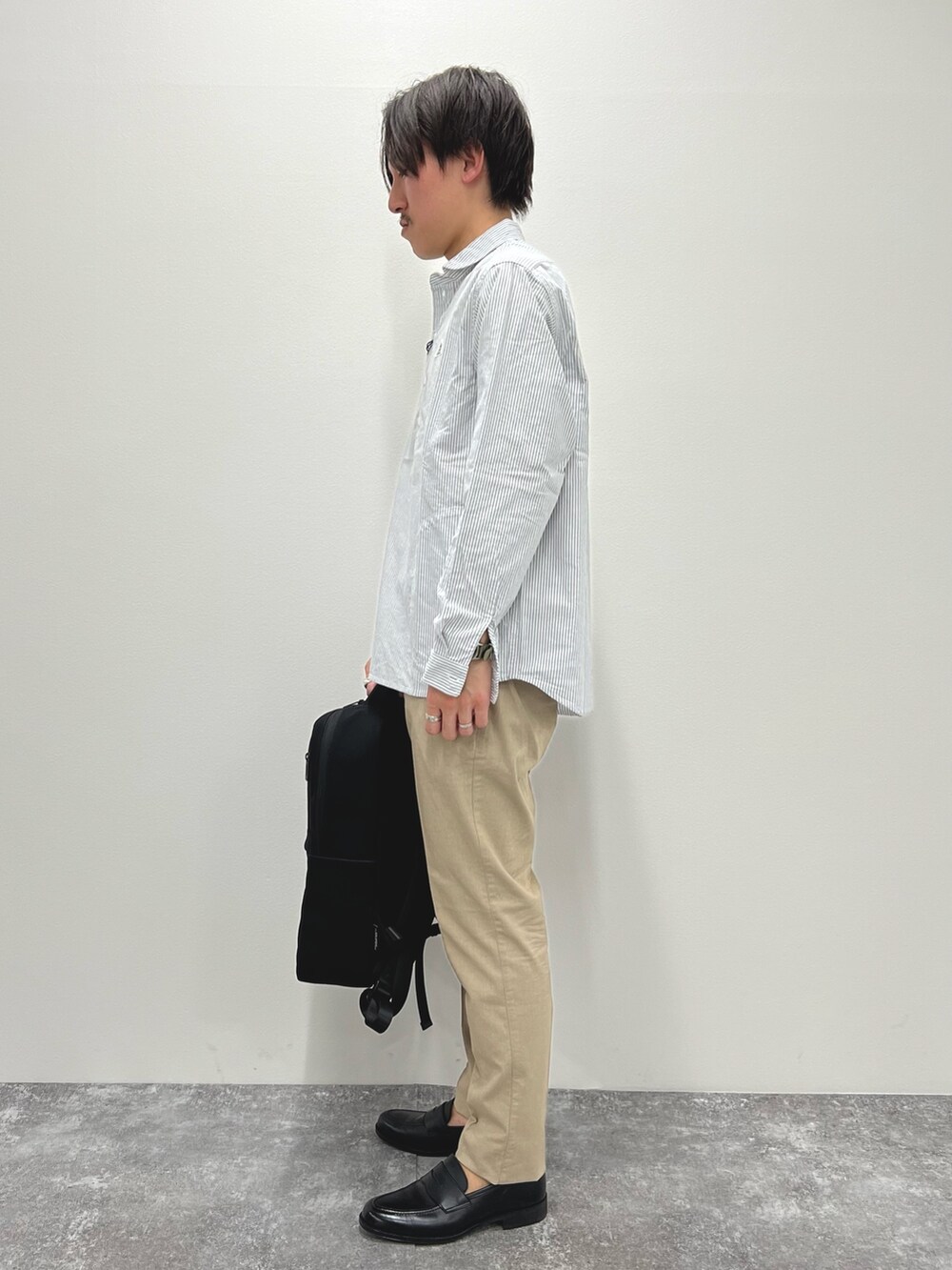 ブラック系のシャツ/ブラウス、ベージュ系のチノパンツ、ブラック系のバックパック/リュックを着用したメンズの春コーディネートの3枚目の写真