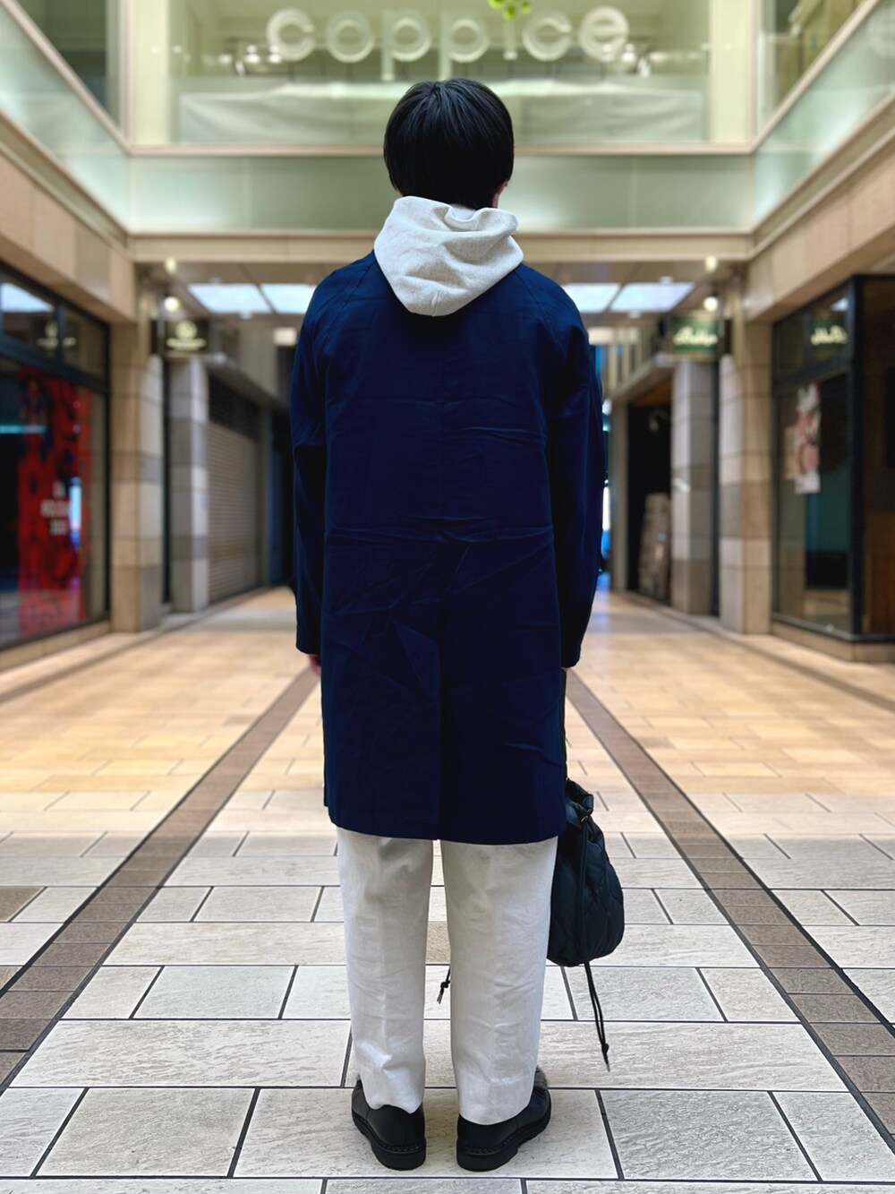 グレー系のパーカー、ブルー系のステンカラーコート、グレー系のトートバッグを着用したメンズの冬コーディネートの5枚目の写真