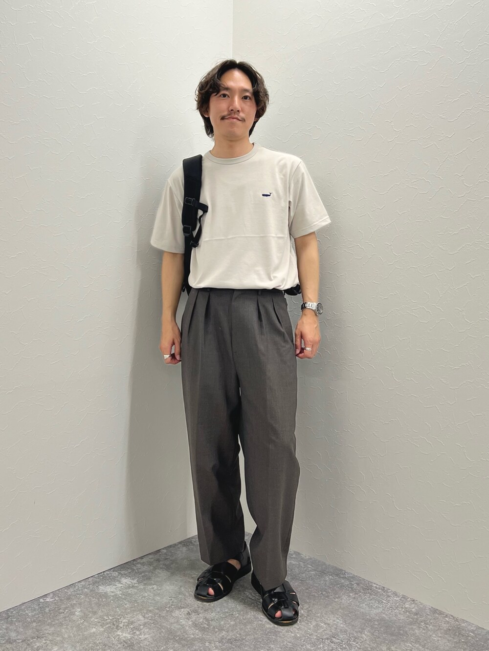 ベージュ系のTシャツ/カットソー、ブラック系のバックパック/リュック、ブラック系のサンダルを着用したメンズの春コーディネートの4枚目の写真