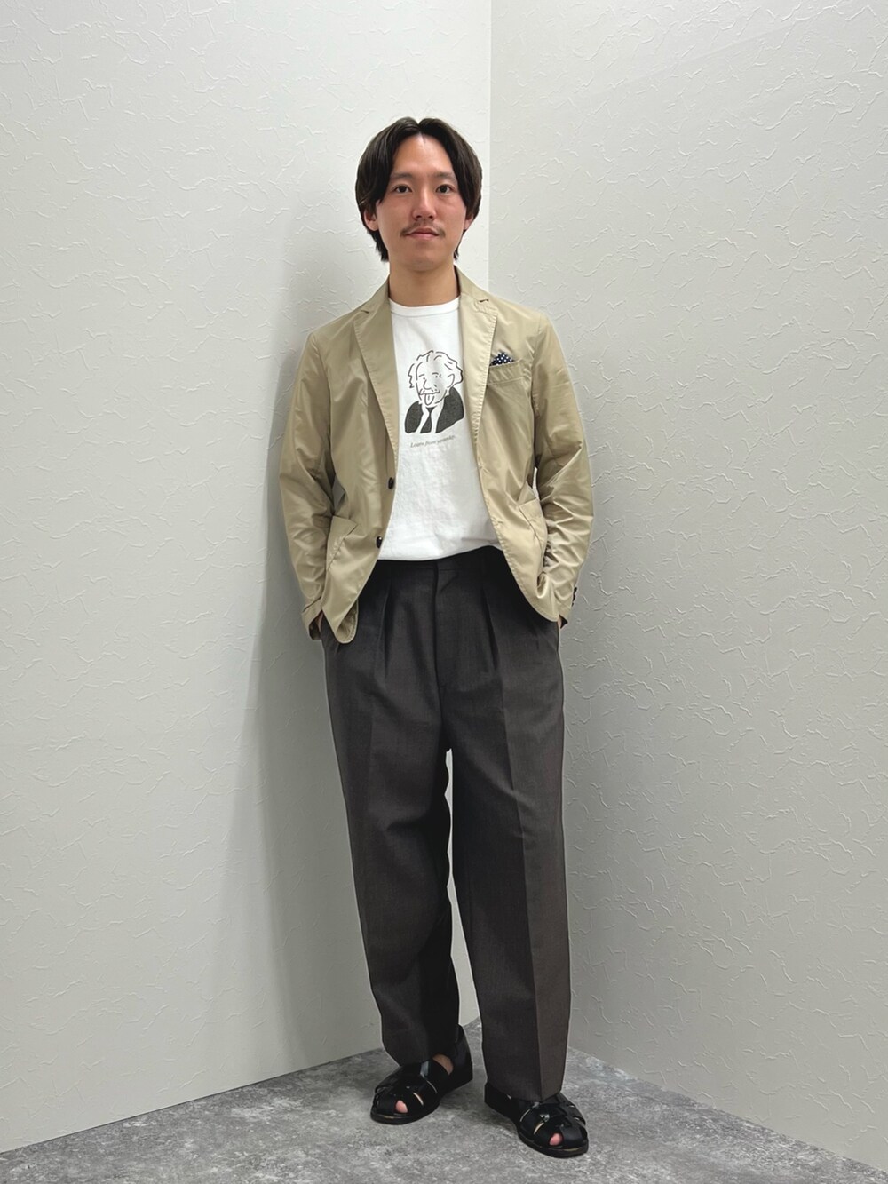 ベージュ系のテーラードジャケット、ホワイト系のTシャツ/カットソー、ブラック系のサンダルを着用したメンズの春コーディネートの3枚目の写真