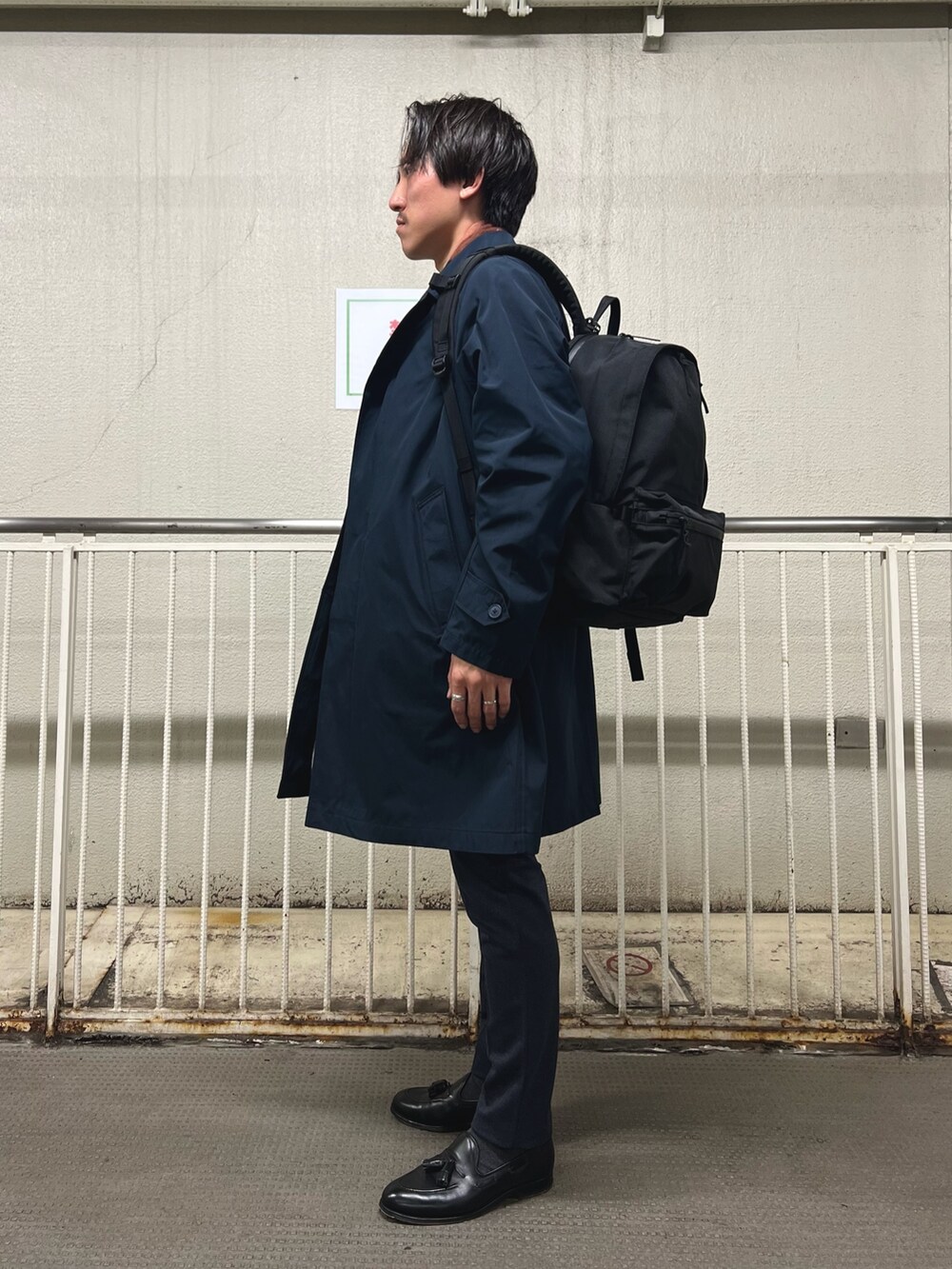 ブラック系のバックパック/リュック、ホワイト系のTシャツ/カットソー、ブルー系のステンカラーコートを着用したメンズの秋コーディネートの5枚目の写真