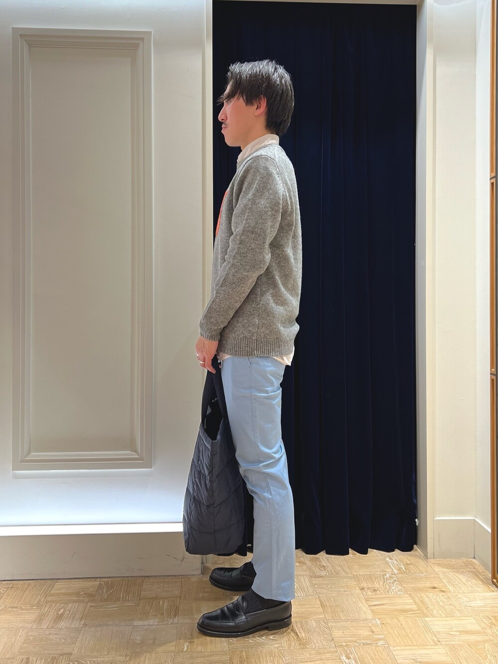 グレー系のニット/セーター、ベージュ系のシャツ/ブラウス、ブルー系のチノパンツを着用したメンズの冬コーディネートの4枚目の写真