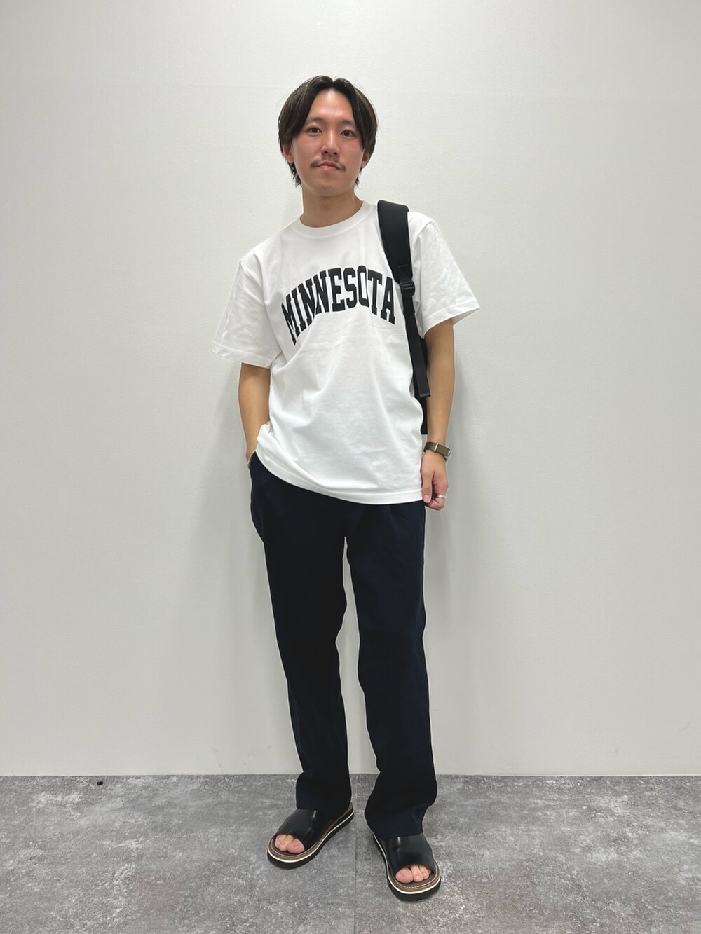 ホワイト系のTシャツ/カットソー、ブラック系のバックパック/リュック、ブラック系のサンダルを着用したメンズの春コーディネートの3枚目の写真