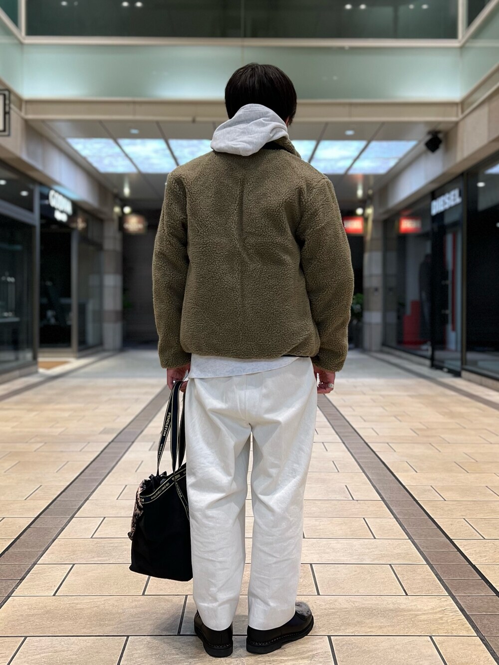 ベージュ系のダウンジャケット/コート、グレー系のパーカー、ブラック系のトートバッグを着用したメンズの秋コーディネートの5枚目の写真