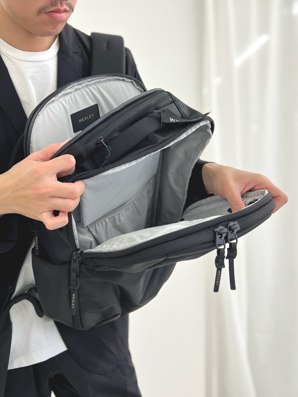 ブラック系のバックパック/リュック、ブルー系のテーラードジャケット、ブルー系のその他パンツを着用したメンズの夏コーディネートの8枚目の写真