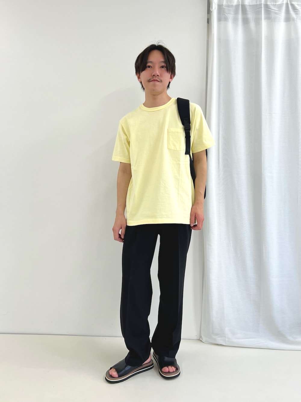 イエロー系のTシャツ/カットソー、ブルー系のその他パンツ、ブラック系のバックパック/リュックを着用したメンズの春コーディネートの3枚目の写真