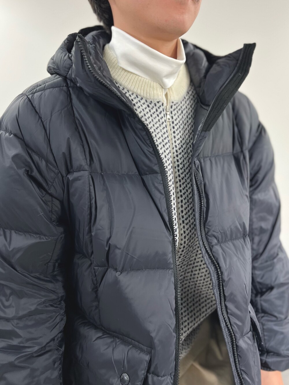 ブラック系のダウンジャケット/コート、ホワイト系のカーディガン/ボレロ、ホワイト系のTシャツ/カットソーを着用したメンズの冬コーディネートの8枚目の写真