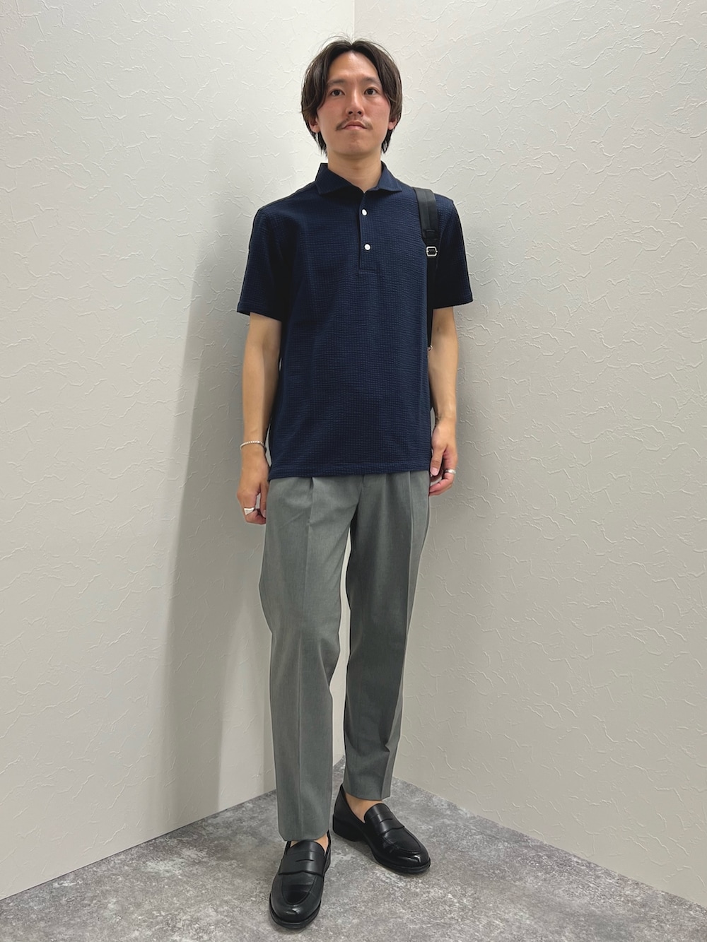 ブルー系のポロシャツ、グレー系のその他パンツ、ブラック系のトートバッグを着用したメンズの夏コーディネートの4枚目の写真