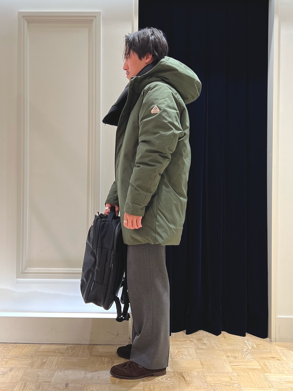 グリーン系のシャツ/ブラウス、ブラック系のバックパック/リュック、グリーン系のダウンジャケット/コートを着用したメンズの冬コーディネートの6枚目の写真