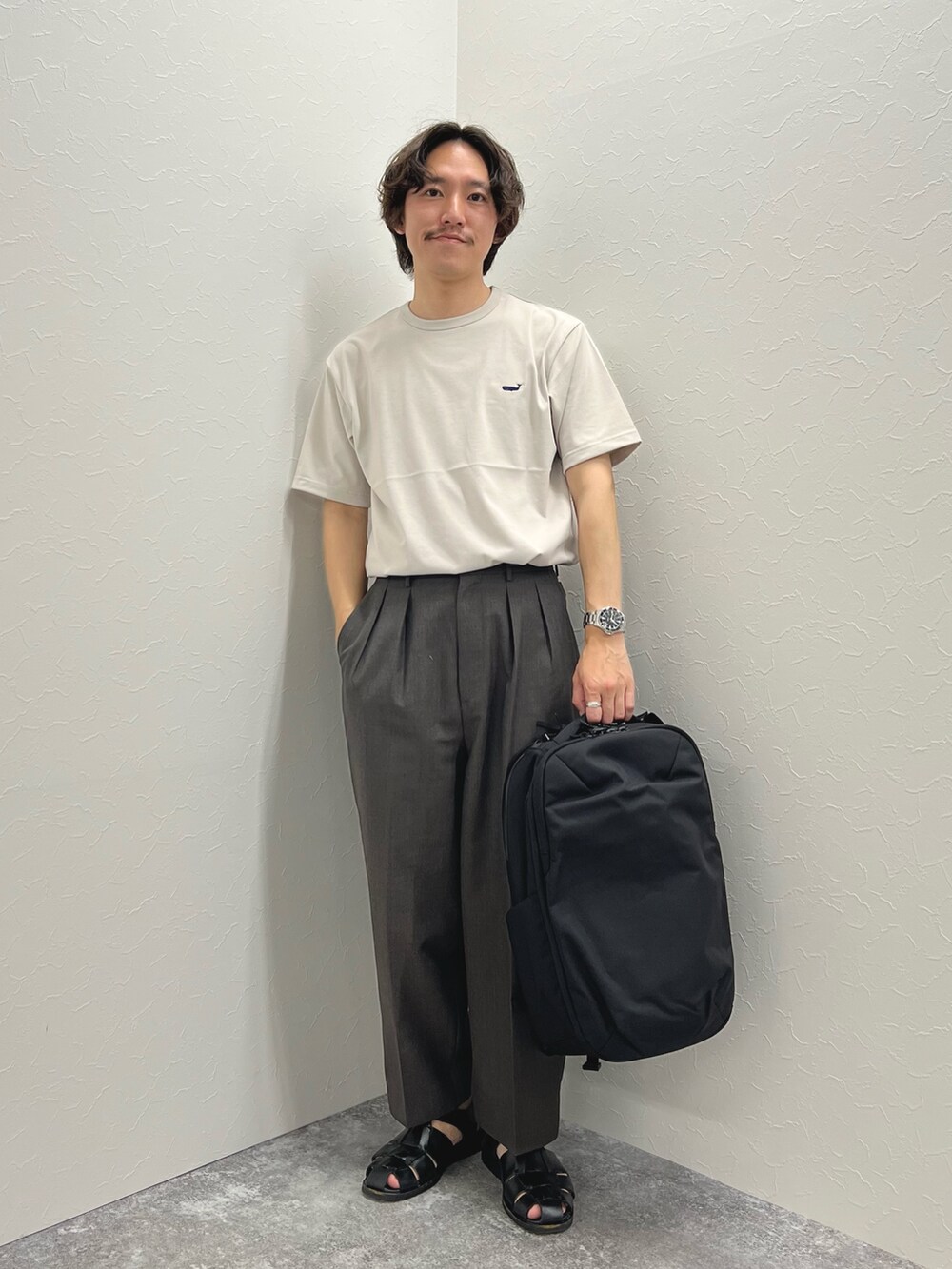 ベージュ系のTシャツ/カットソー、ブラック系のバックパック/リュック、ブラック系のサンダルを着用したメンズの春コーディネートの3枚目の写真