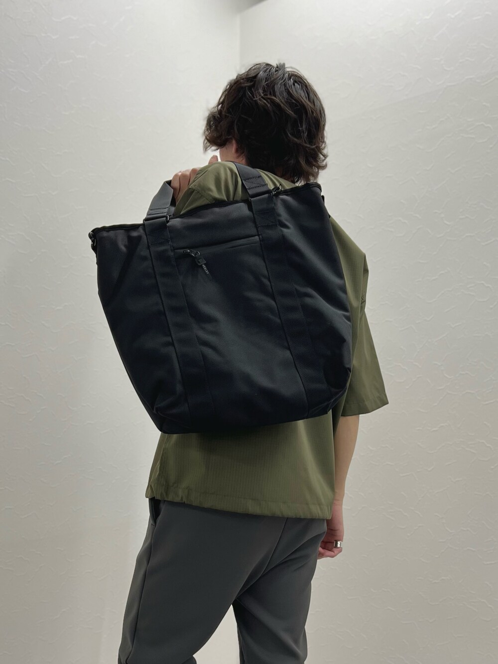 グリーン系のTシャツ/カットソー、ブラック系のトートバッグ、グレー系のその他パンツを着用したメンズの春コーディネートの7枚目の写真