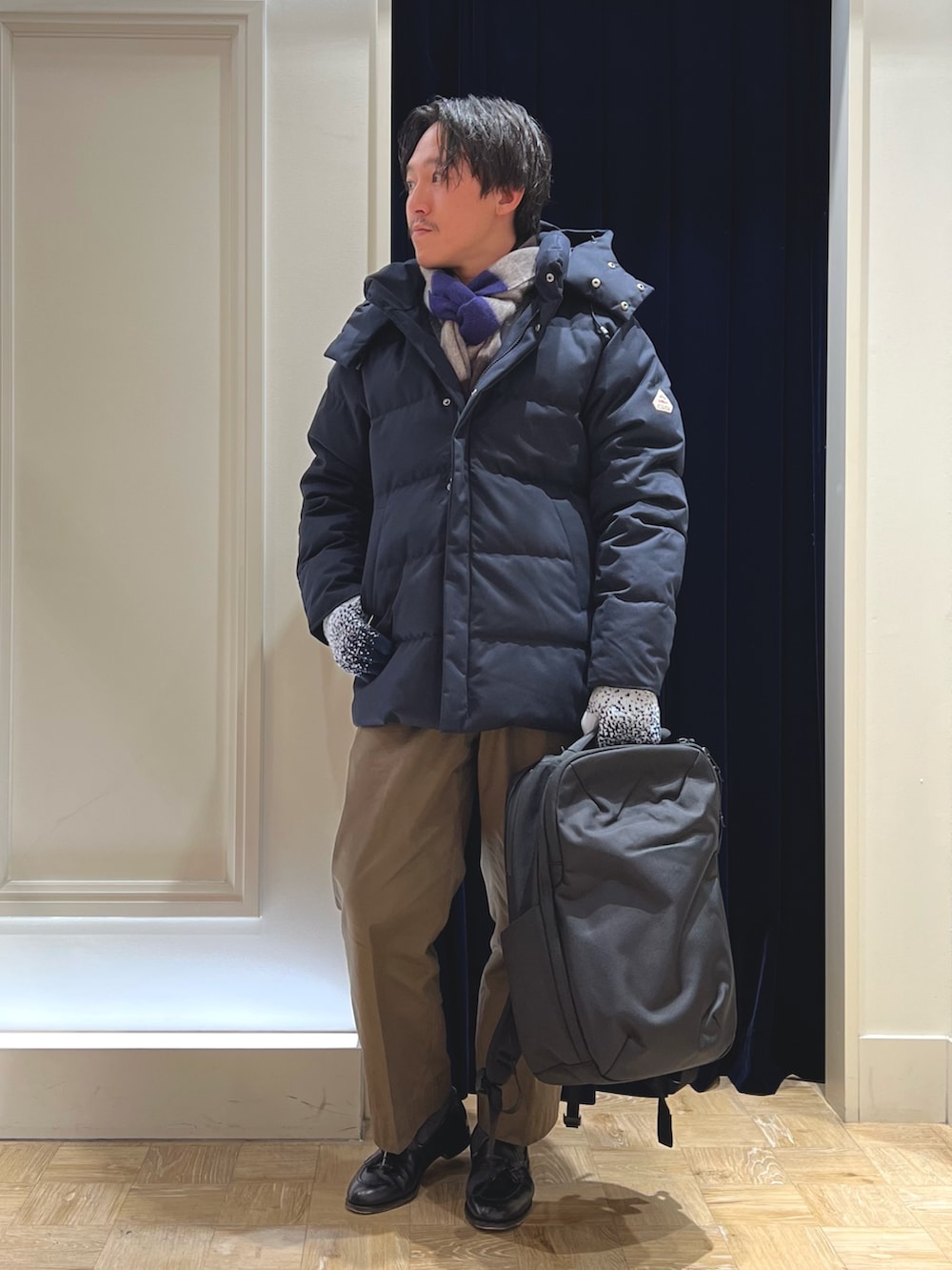 ブルー系のダウンジャケット/コート、ブラック系のバックパック/リュック、グレー系のマフラーを着用したメンズの冬コーディネートの4枚目の写真