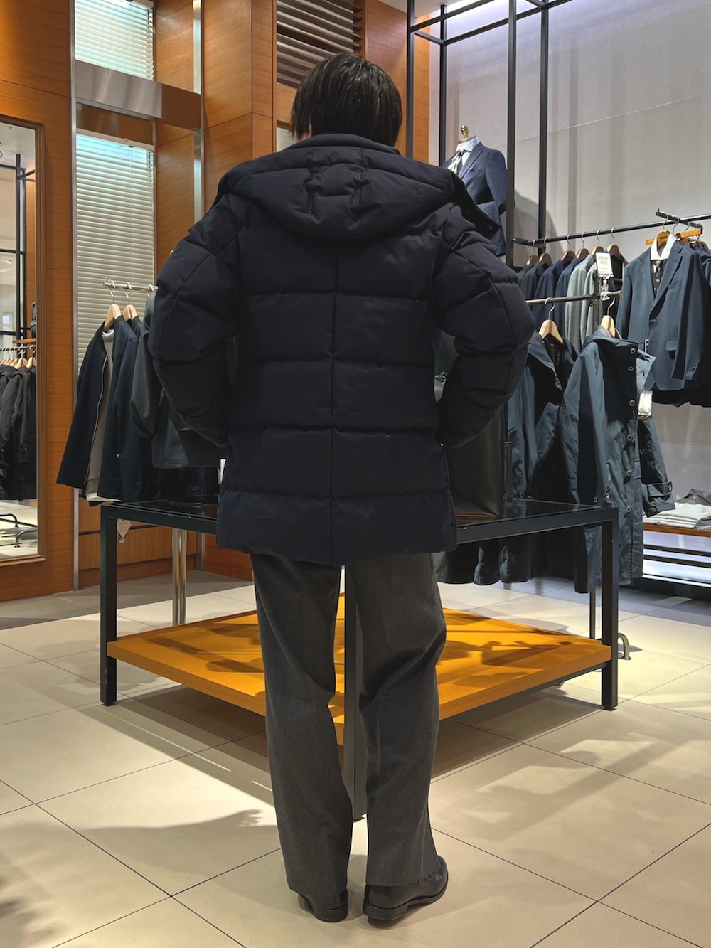 ブルー系のダウンジャケット/コート、ブラック系のトートバッグ、ブラック系のローファーを着用したメンズの冬コーディネートの6枚目の写真