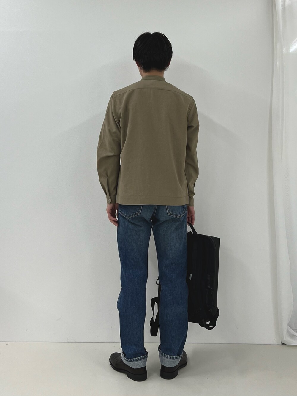 ホワイト系のTシャツ/カットソー、ベージュ系のブルゾン、ブラック系のバックパック/リュックを着用したメンズの春コーディネートの4枚目の写真