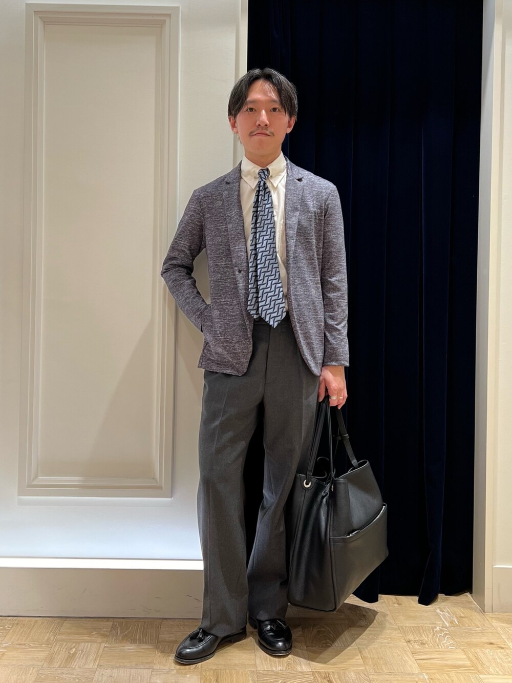 グレー系のカーディガン/ボレロ、ブルー系のネクタイ、ブラック系のトートバッグを着用したメンズの冬コーディネートの2枚目の写真