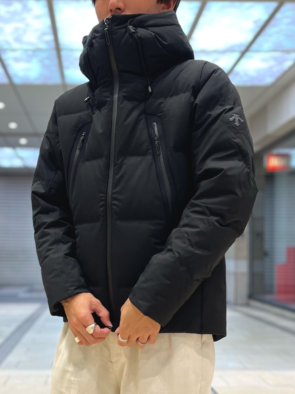 ベージュ系のトートバッグ、ベージュ系のTシャツ/カットソー、ブラック系のダウンジャケット/コートを着用したメンズの秋コーディネートの7枚目の写真