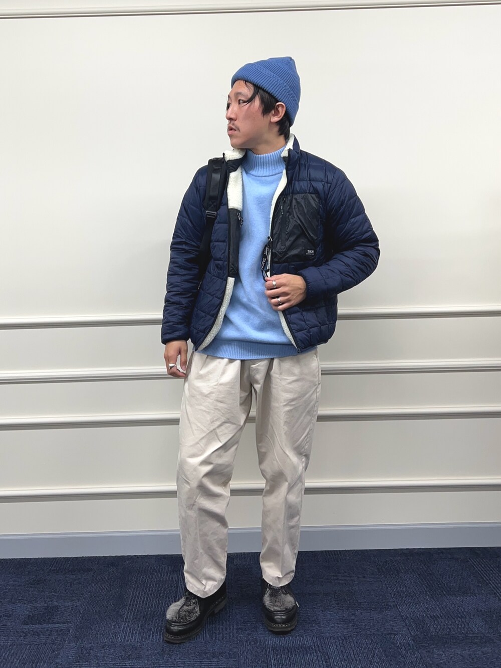 ブルー系のニット/セーター、ホワイト系のブルゾン、ブラック系のバックパック/リュックを着用したメンズの秋コーディネートの3枚目の写真
