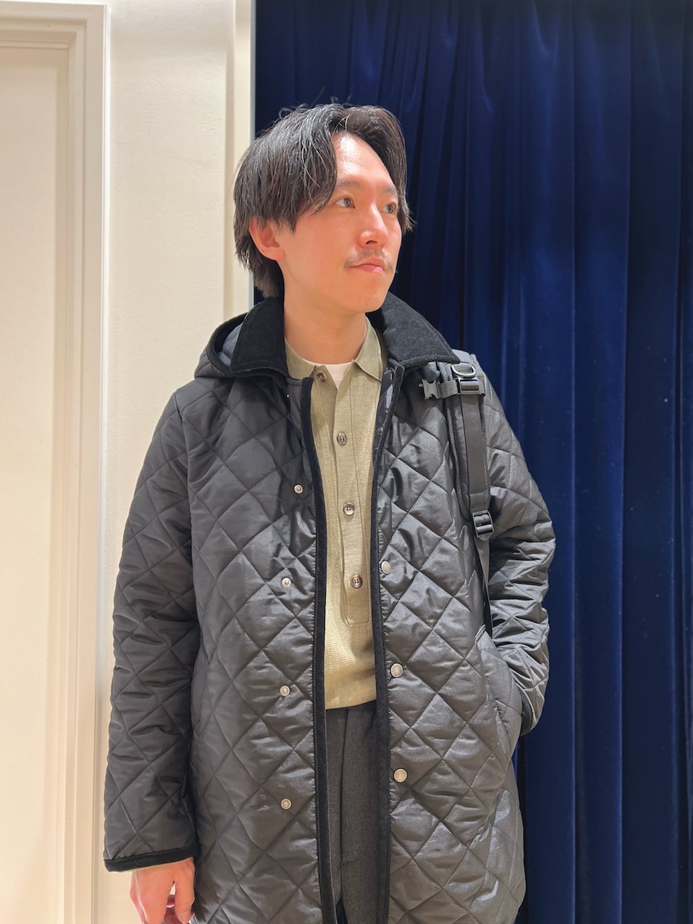 ブラック系のステンカラーコート、ブラック系のローファー、ブラック系のバックパック/リュックを着用したメンズの冬コーディネートの5枚目の写真