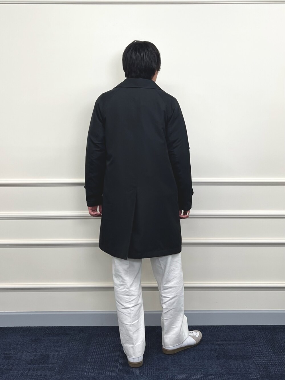 ブラック系のステンカラーコート、ホワイト系のデニムパンツ、オレンジ系のニット/セーターを着用したメンズの冬コーディネートの6枚目の写真