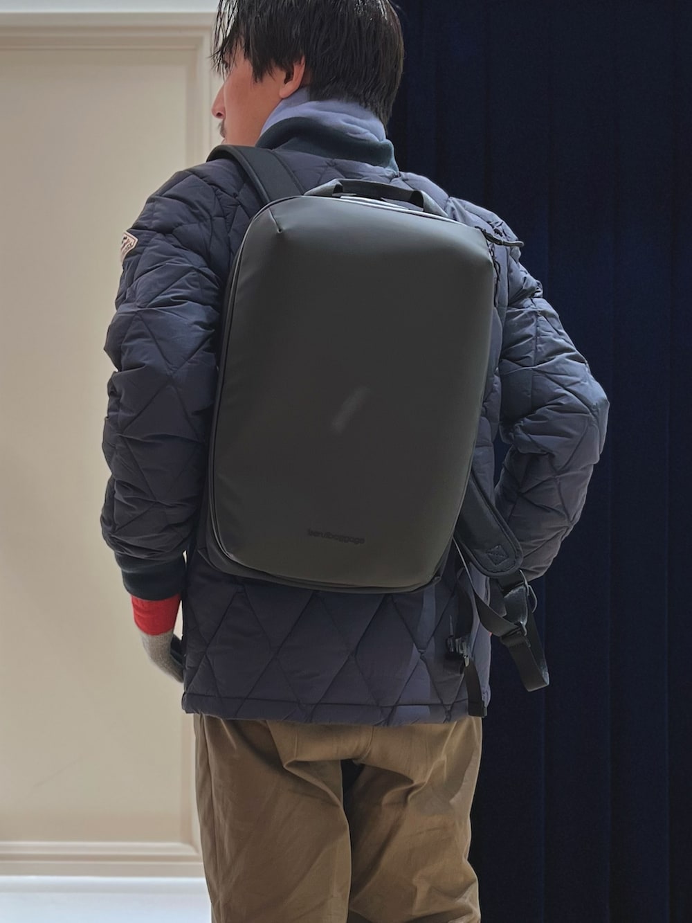 ブルー系のダウンジャケット/コート、ブラック系のバックパック/リュック、ブルー系のマフラーを着用したメンズの冬コーディネートの7枚目の写真