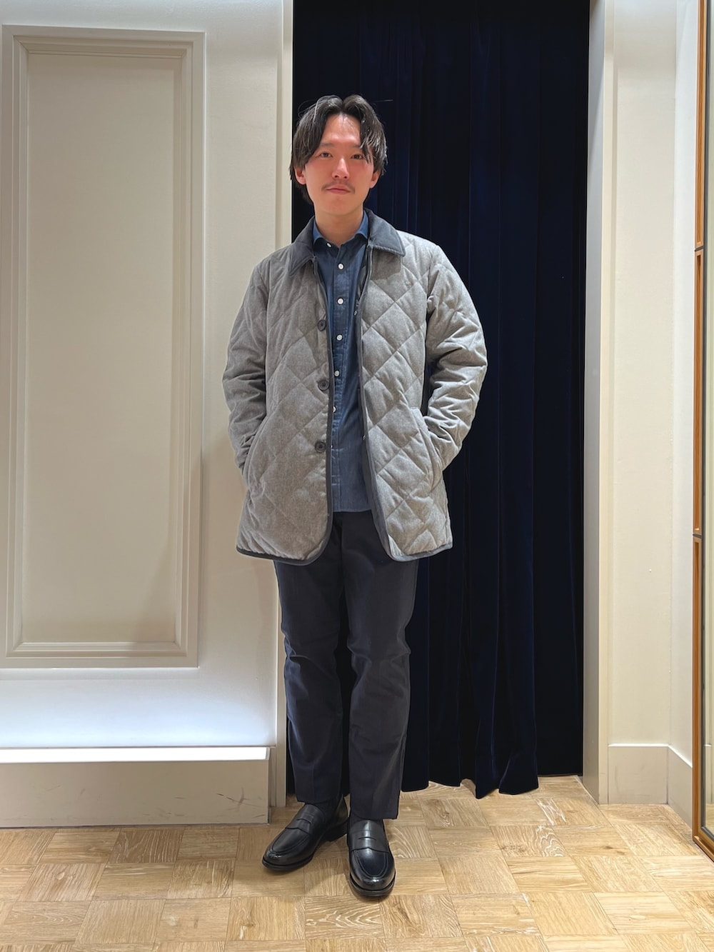 グレー系のダウンジャケット/コート、ブルー系のシャツ/ブラウス、ブラック系のローファーを着用したメンズの冬コーディネートの2枚目の写真